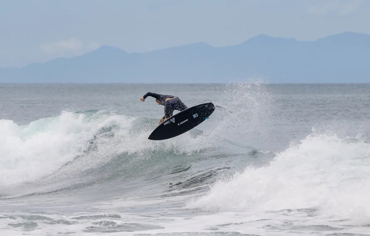 Surfer performs an aerial above a wave.