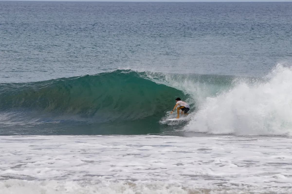 Surfer @maximogattas tucked inside a clean green barrel.