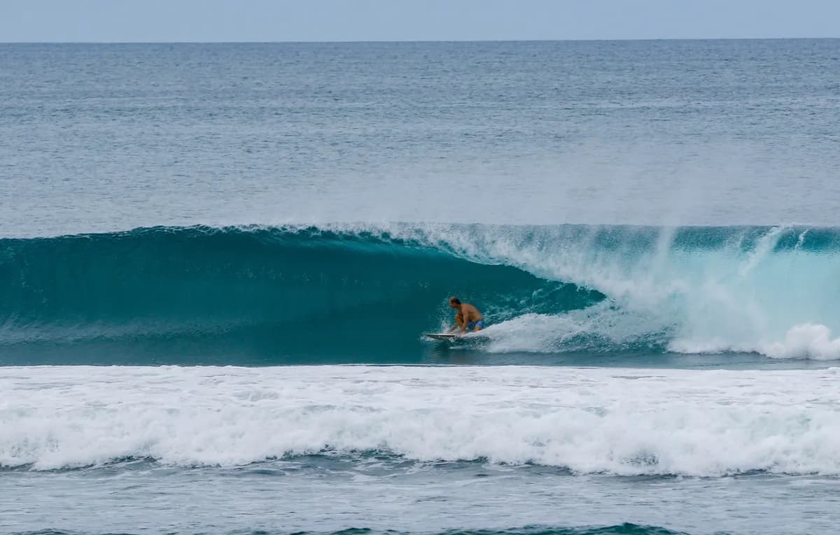 Surfer @carlos-nsr rides inside a perfect blue barrel wave.