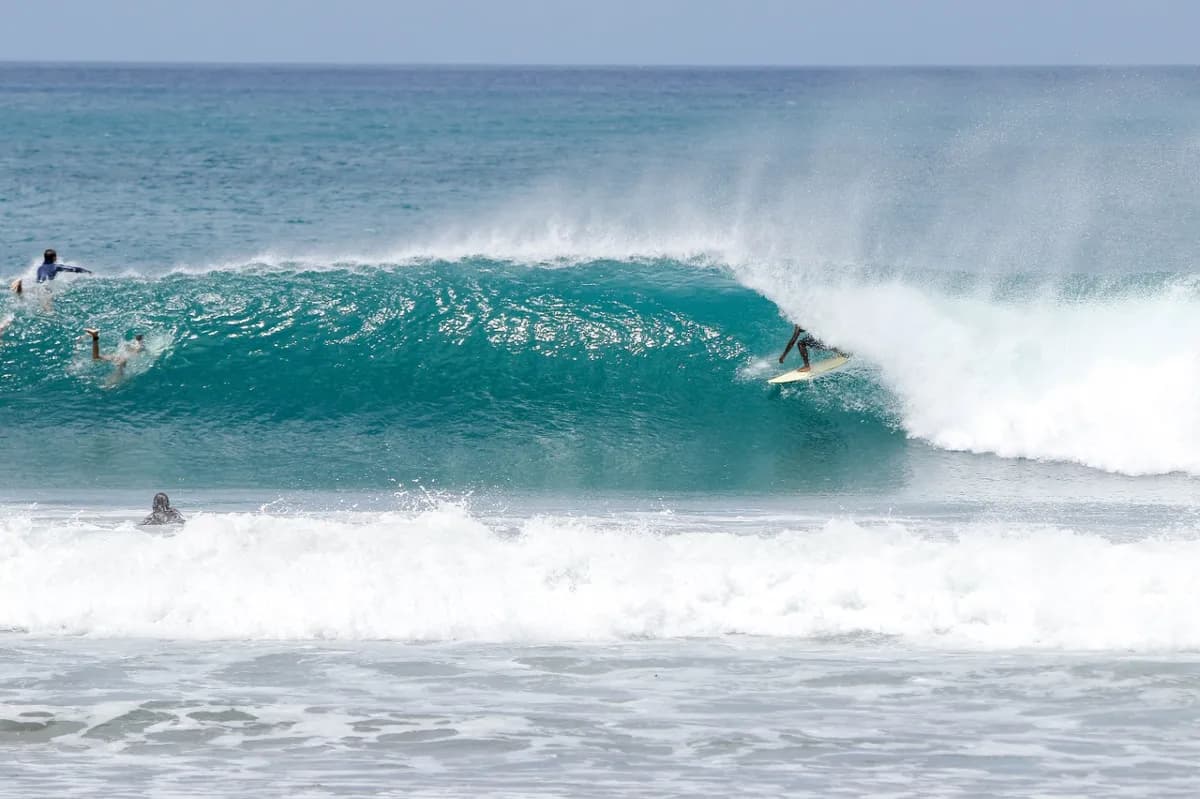 Surfer rides a perfect barrel as waves crash around.