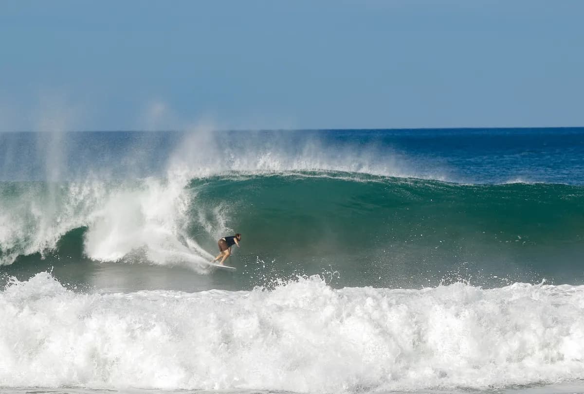 Surfer crouches inside a hollow wave, carving through.