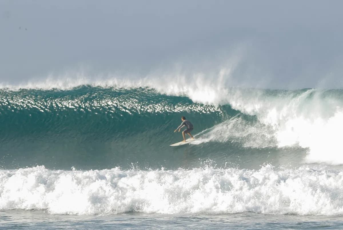 Surfer riding a powerful right on overhead wave.