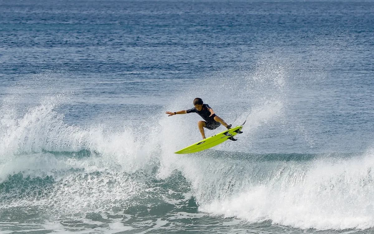 Surfer launches into a stylish air on a clear wave.