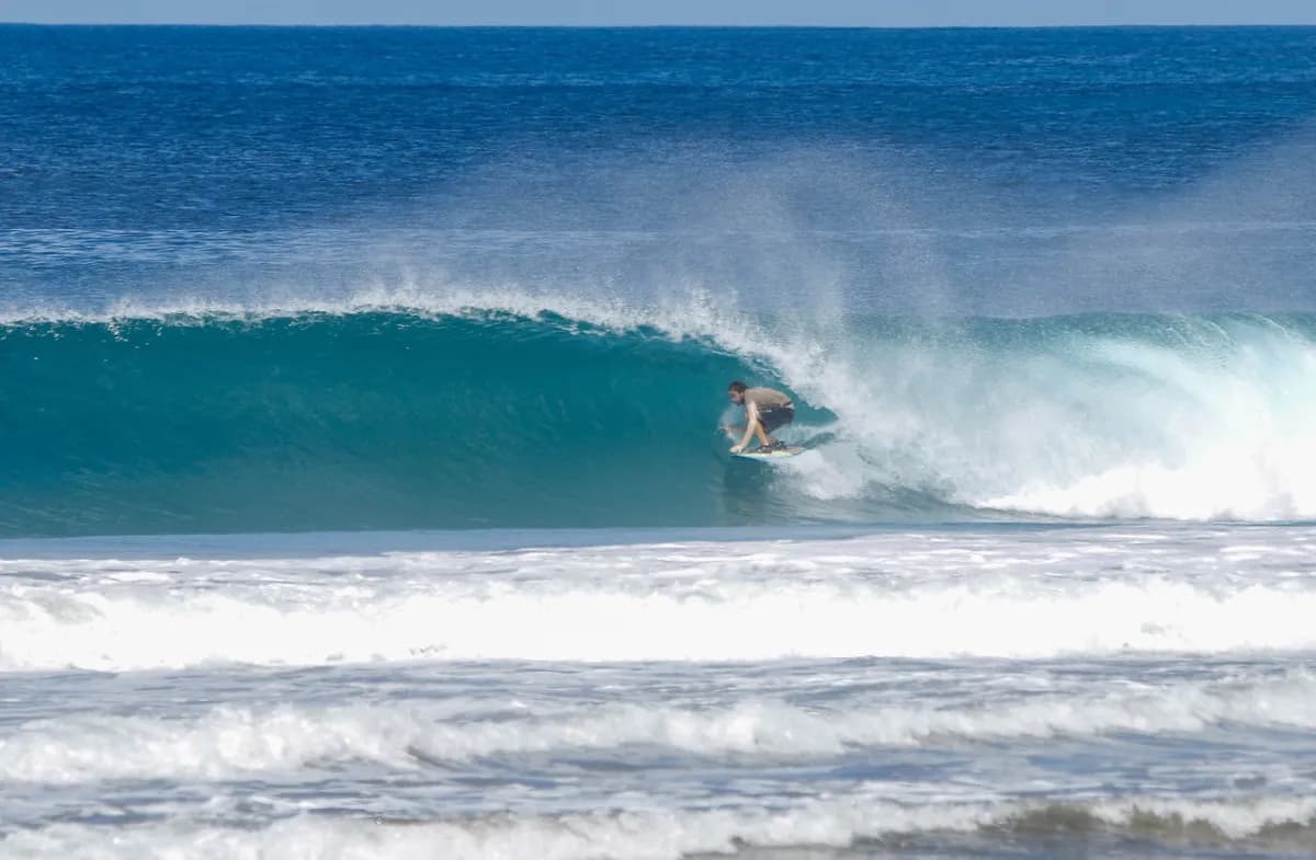 Surfer rides deep inside a hollow barrel wave.