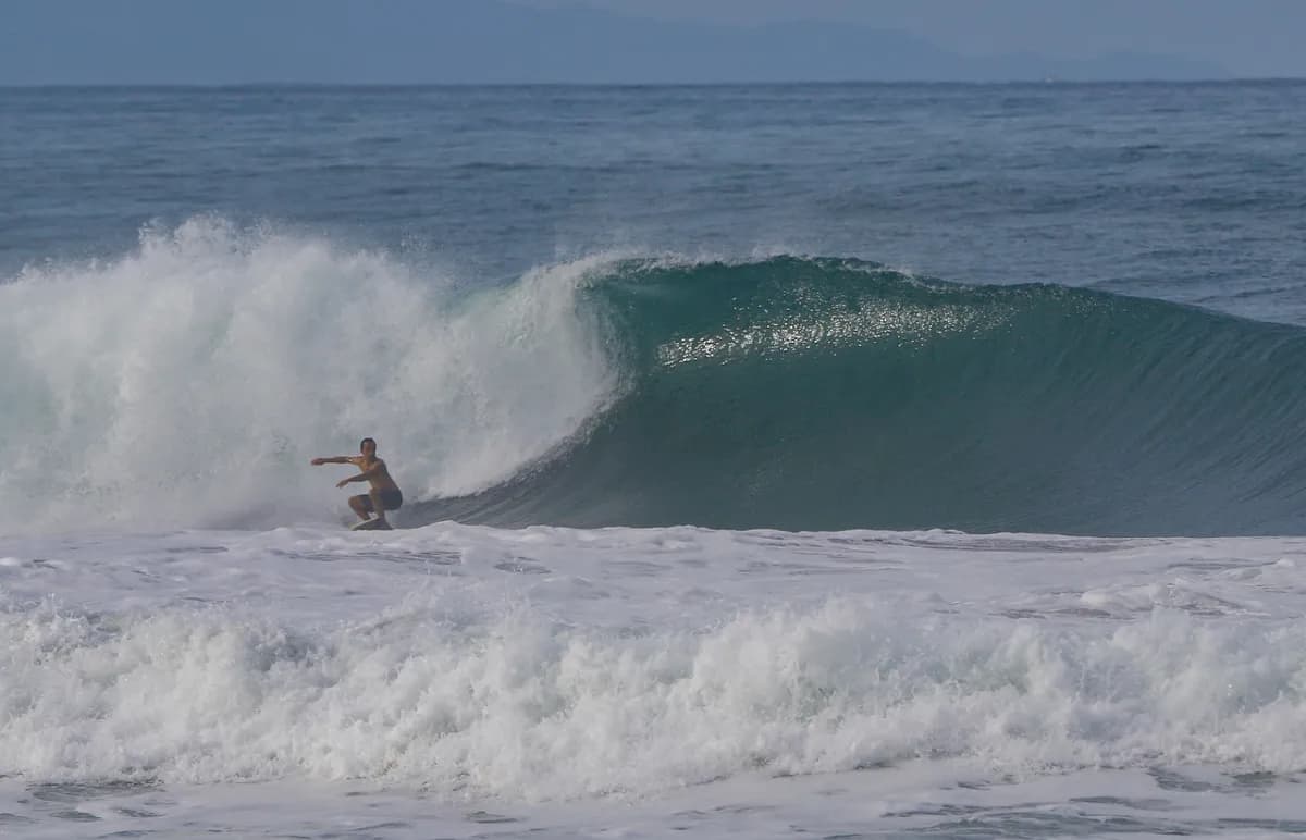 Surfer rides a hollow wave, poised for a barrel.