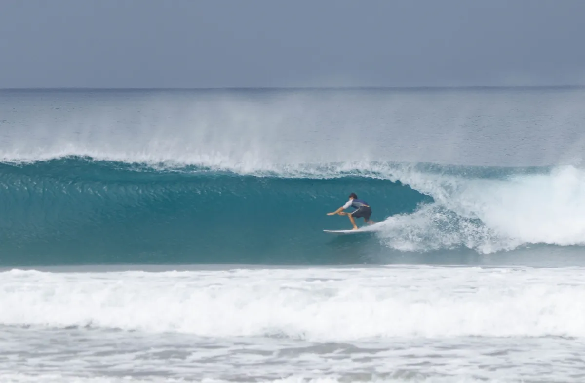Surfer crouches low inside a perfect barreling wave.