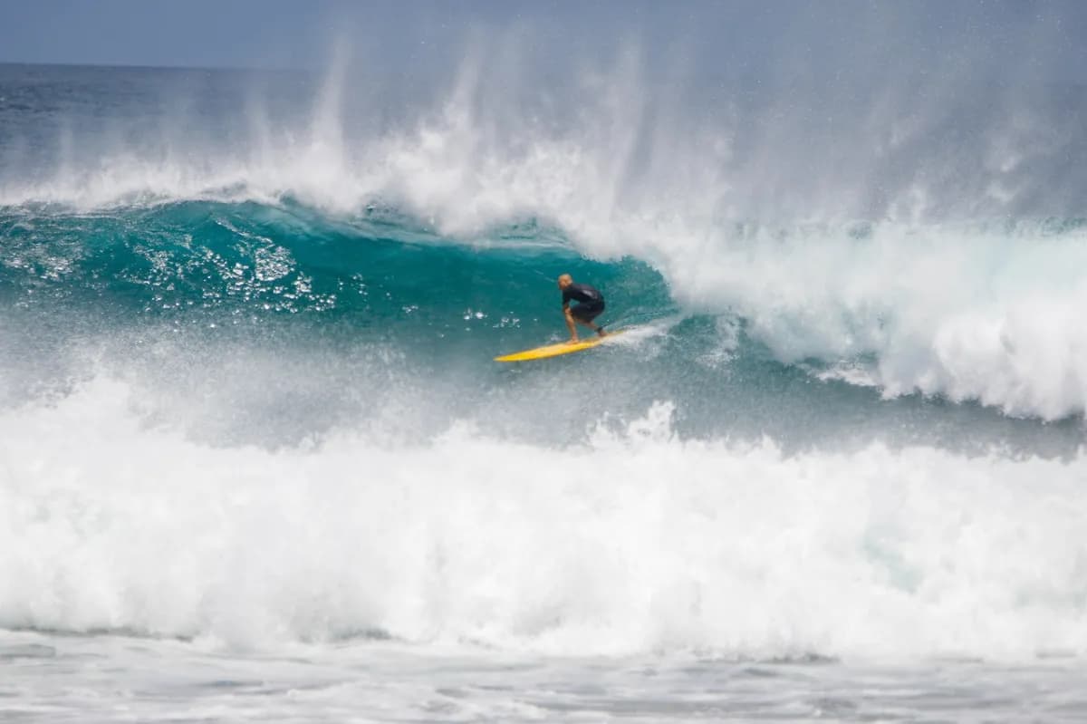 Surfer rides inside a powerful turquoise barrel wave.