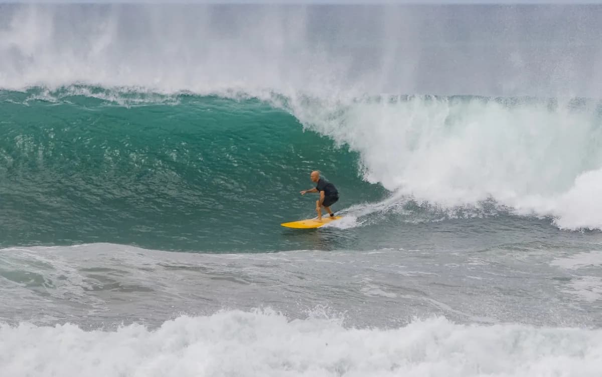 Surfer rides inside a powerful green wave.