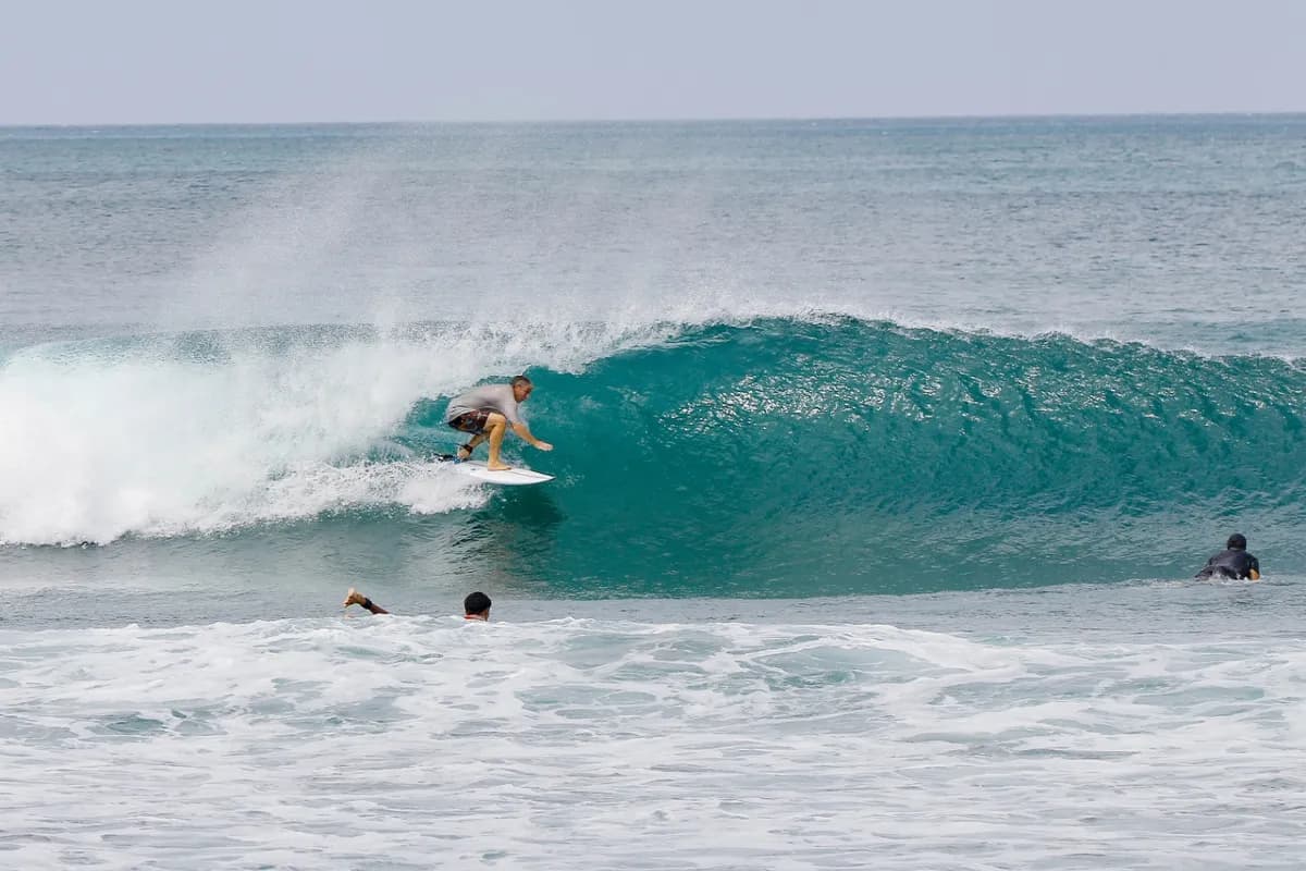 Surfer tucks into a perfect turquoise barrel wave.