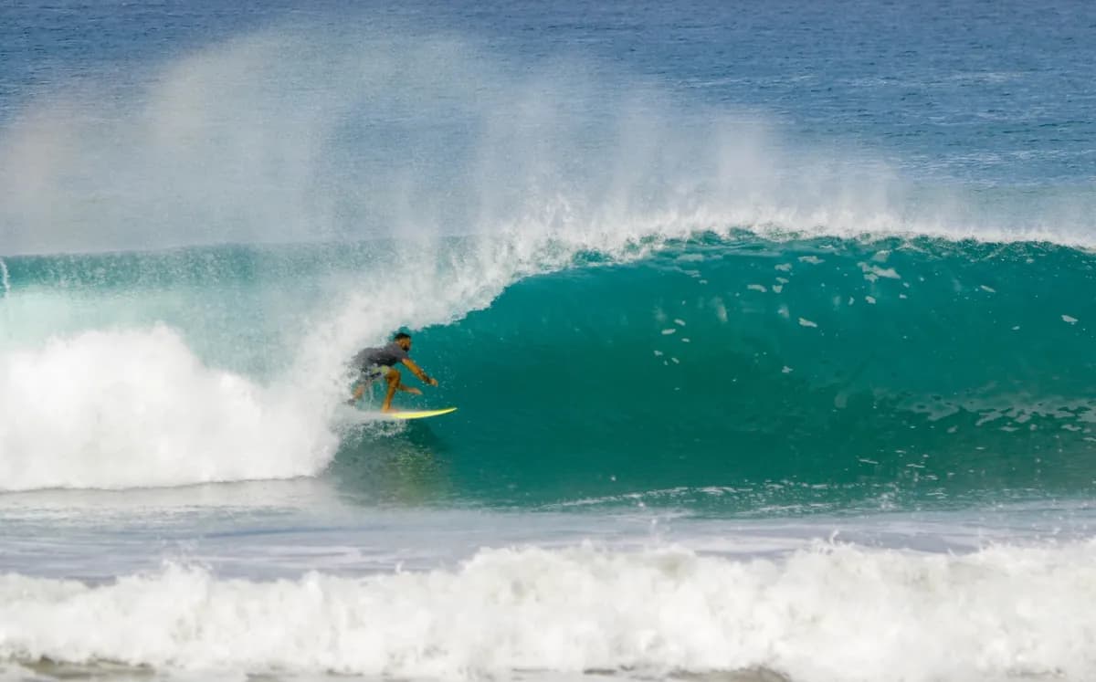 Surfer carves through a pristine, hollow barrel at speed.