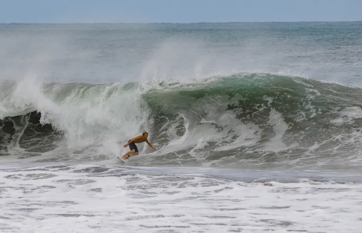 Surfer rides the open face of a crashing wave.