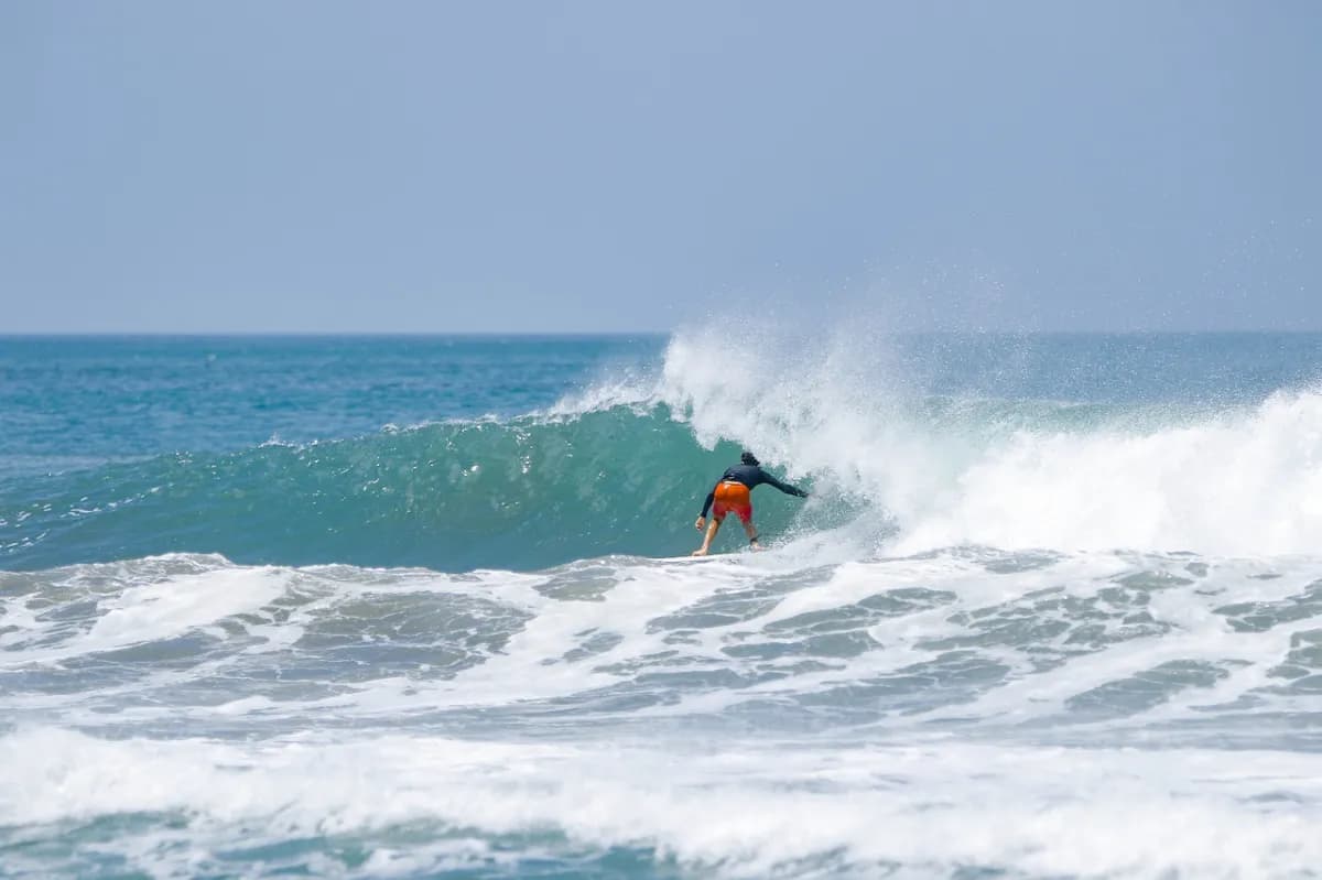 Surfer rides inside a green barrel on a clear day.