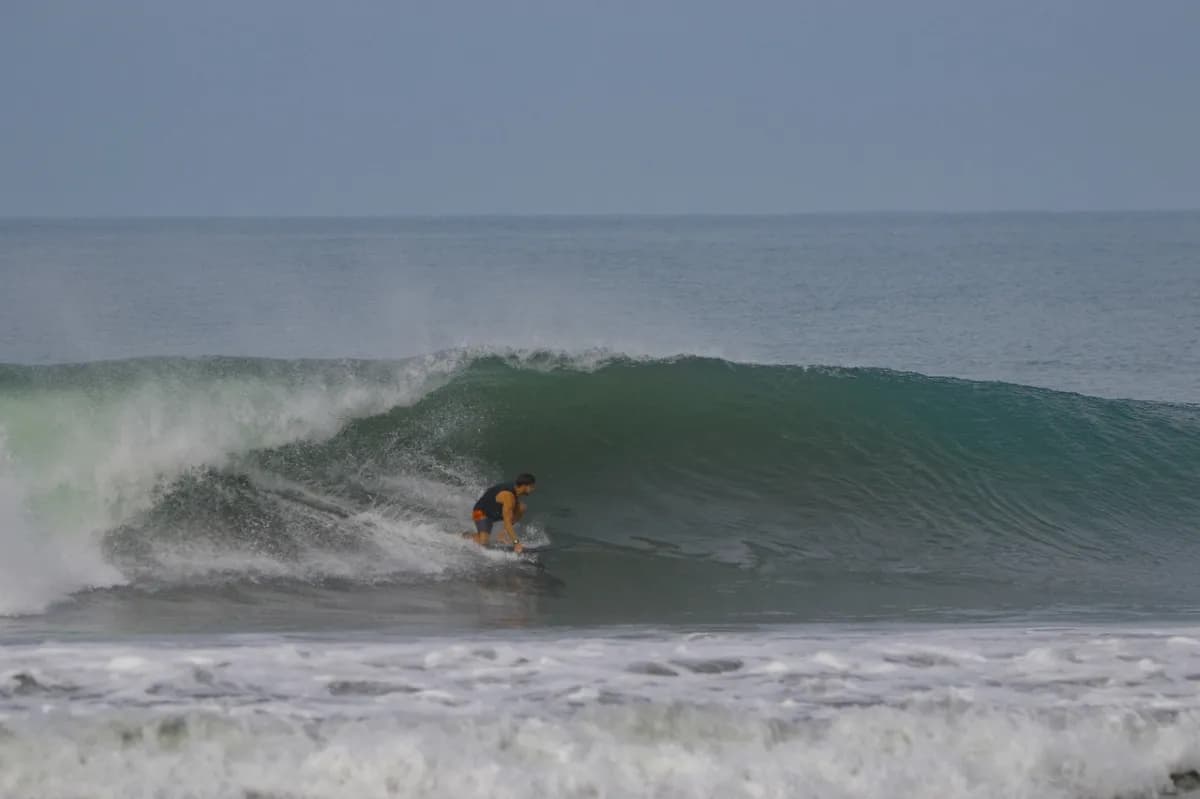 Surfer skillfully rides inside a glassy barrel.