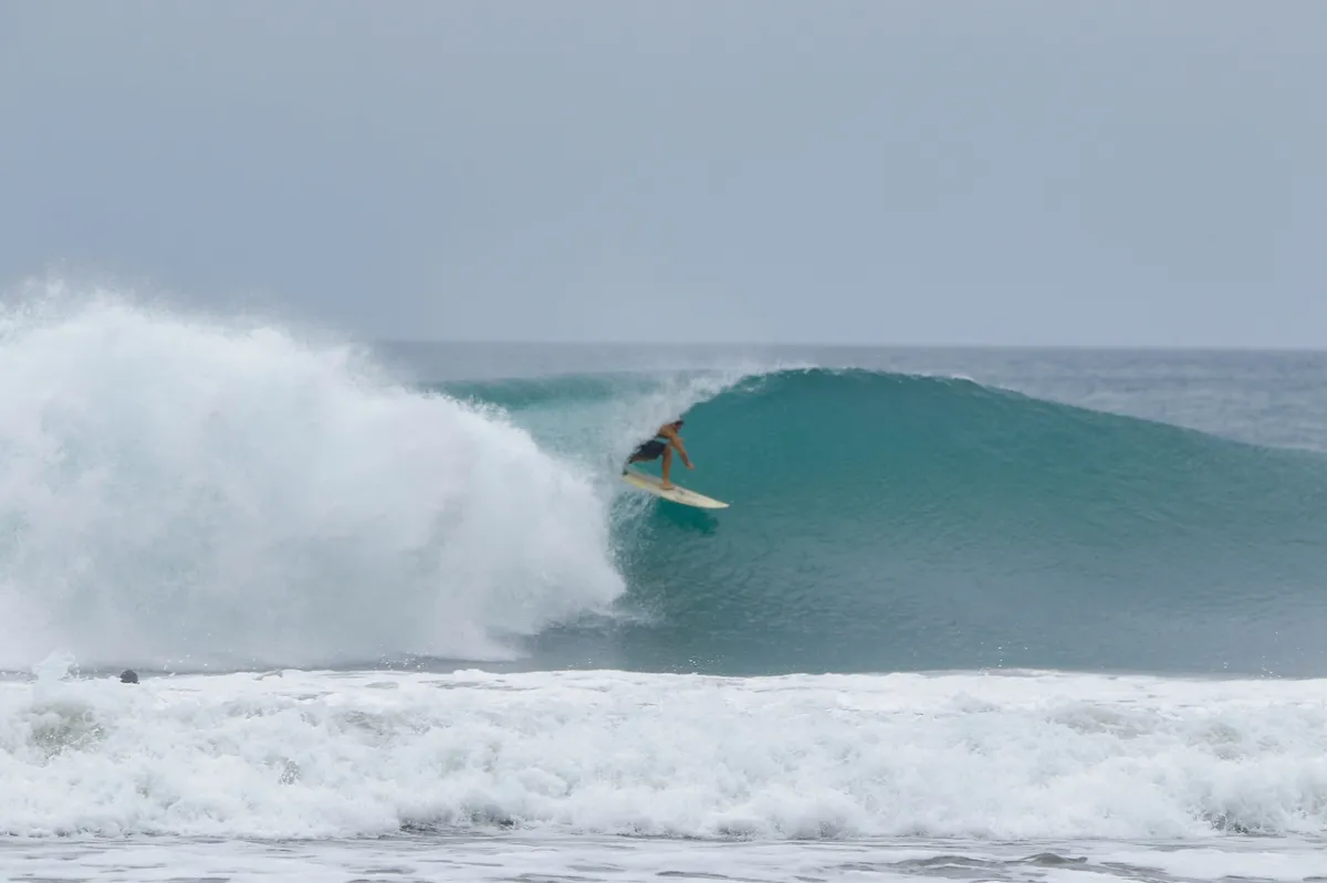 Surfer crouches inside a perfect barrel, board slicing smoothly.