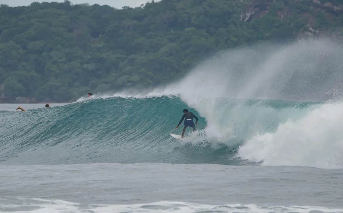 Surfer rides clean right-hand wave with misty spray.