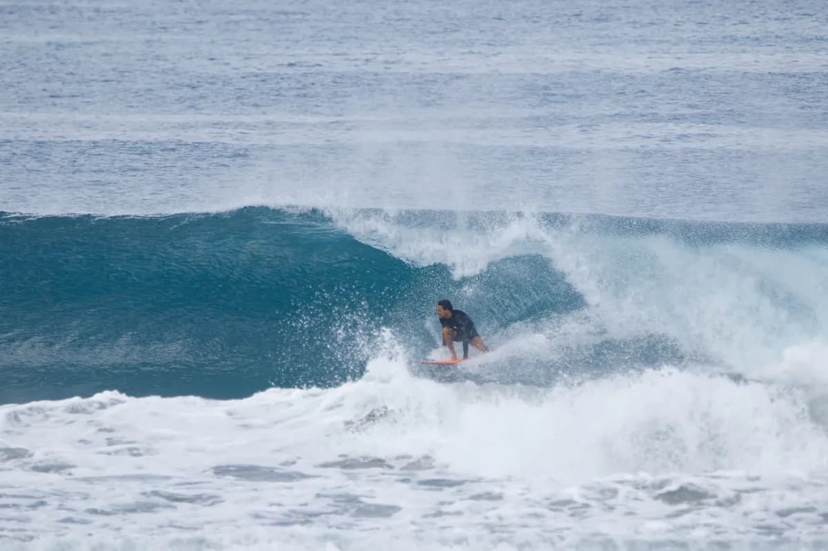 Surfer crouching inside a small barreling wave.