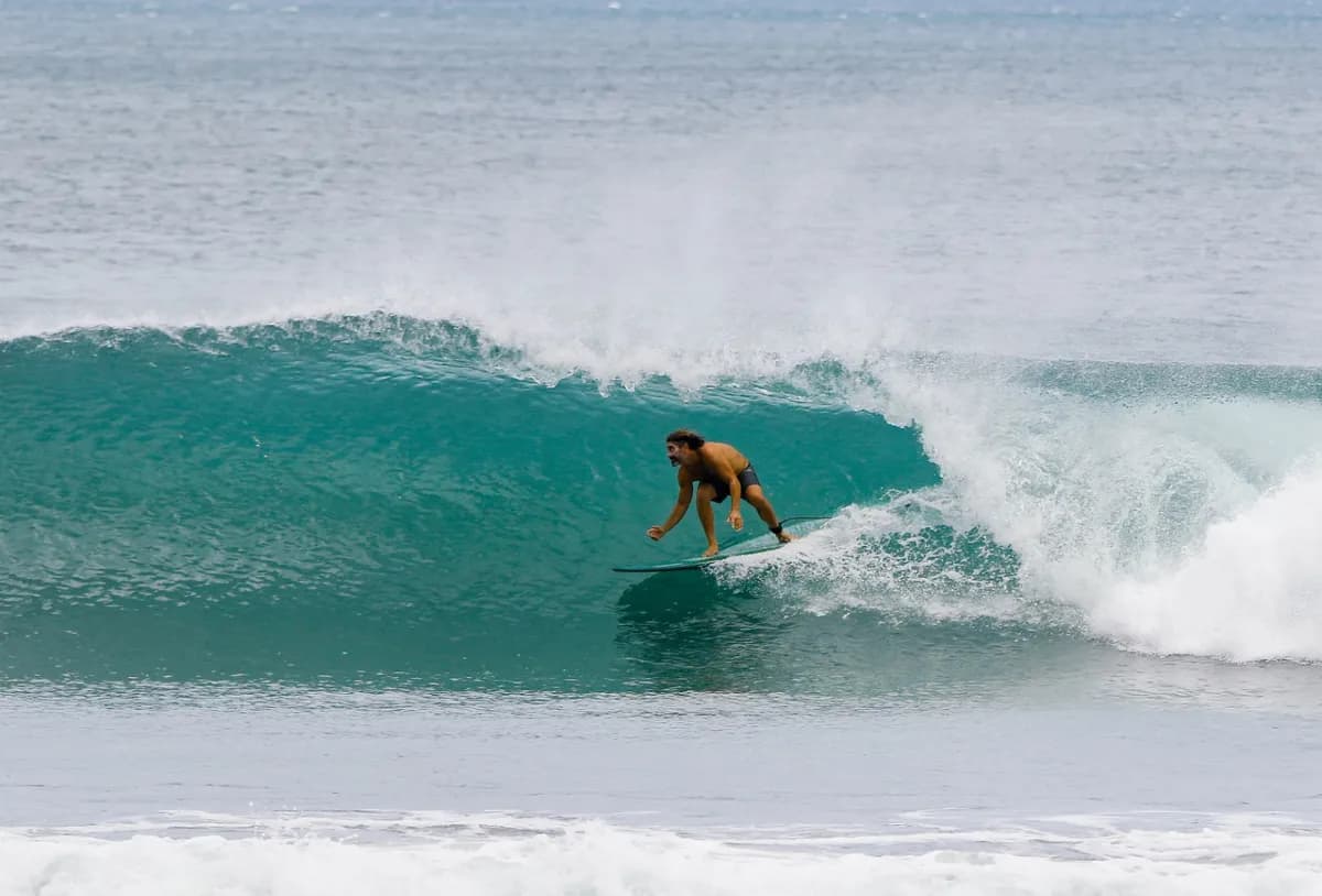 Surfer rides inside a perfect turquoise barrel wave.