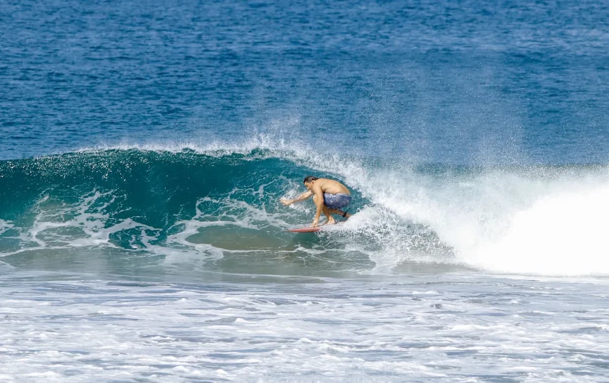 Surfer bauti-yelos tucked into a clear blue barrel.