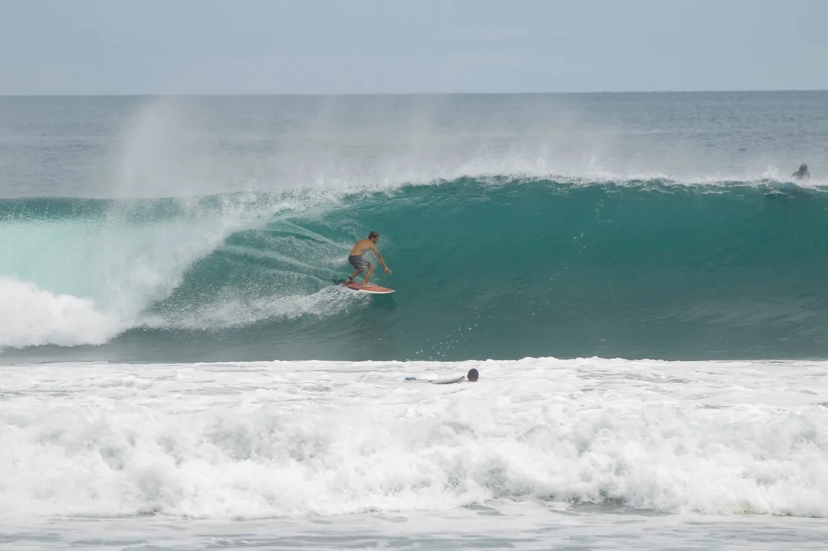 Surfer rides deep barrel with spray flying off the lip.