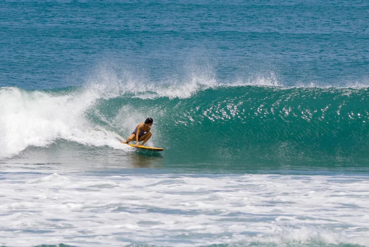 Surfer in a tight barrel on a clear turquoise wave.