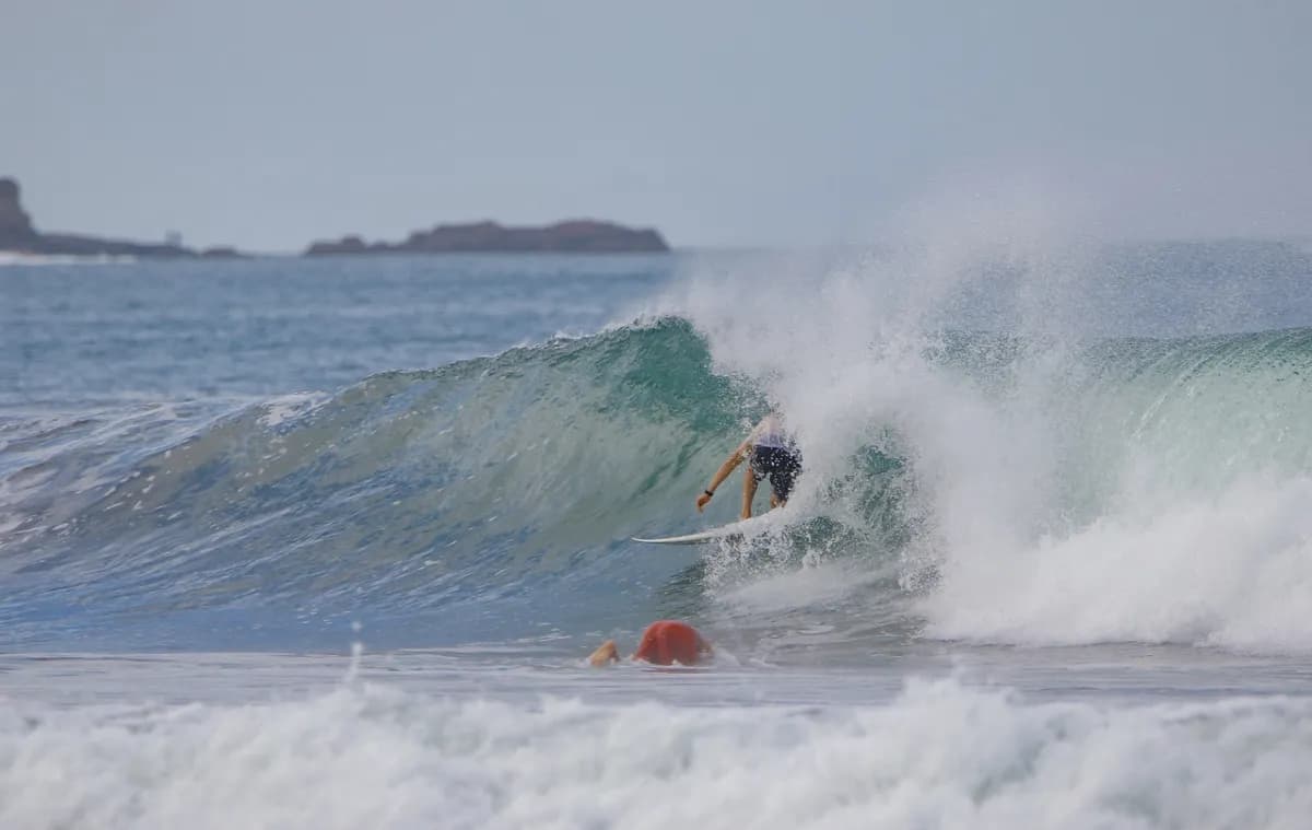 Surfer rides inside a compact, clear barrel.