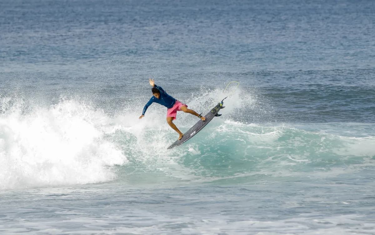 Surfer in mid-air maneuver above whitewater, showcasing skill.