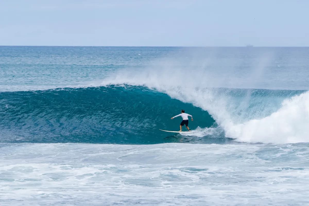 Surfer rides a perfect right-hander in a deep blue barrel.