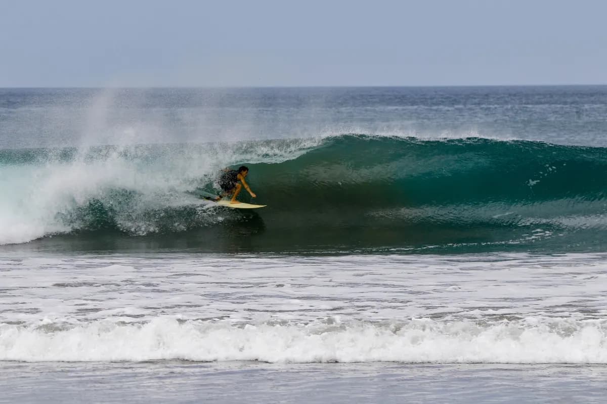 Surfer crouches smoothly in a perfect blue barrel.