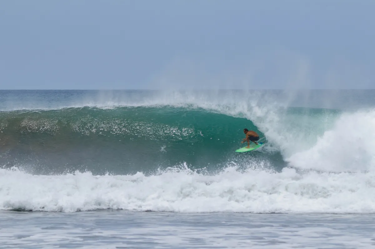 Surfer crouches inside a perfect barrel on a right-hand wave.