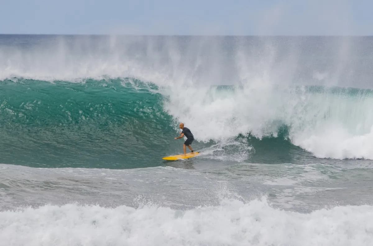 Surfer rides a powerful wave on a yellow board.