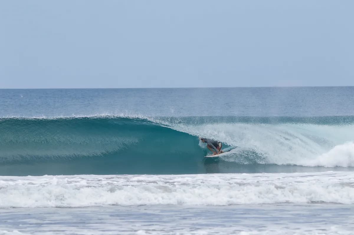 A surfer rides inside a perfect blue barrel wave.