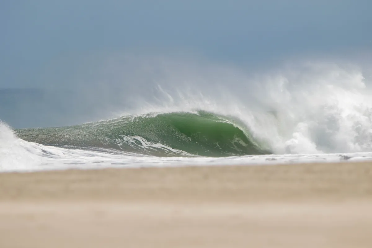 Powerful green barrel crashing close to the shore.
