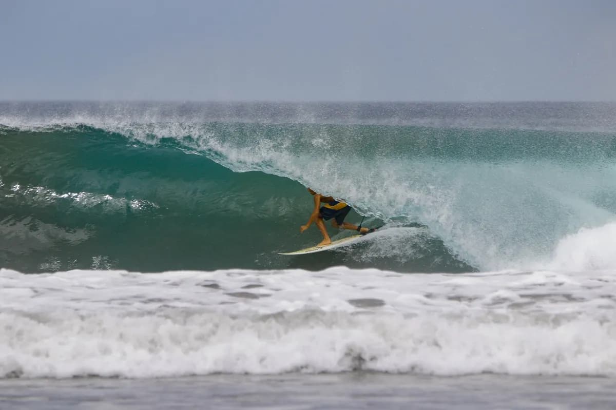 Surfer skillfully rides inside a perfect barrel wave.