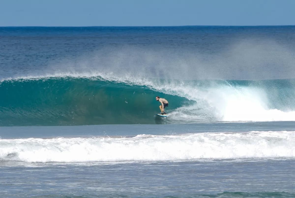 Surfer riding inside a perfect overhead barrel wave.