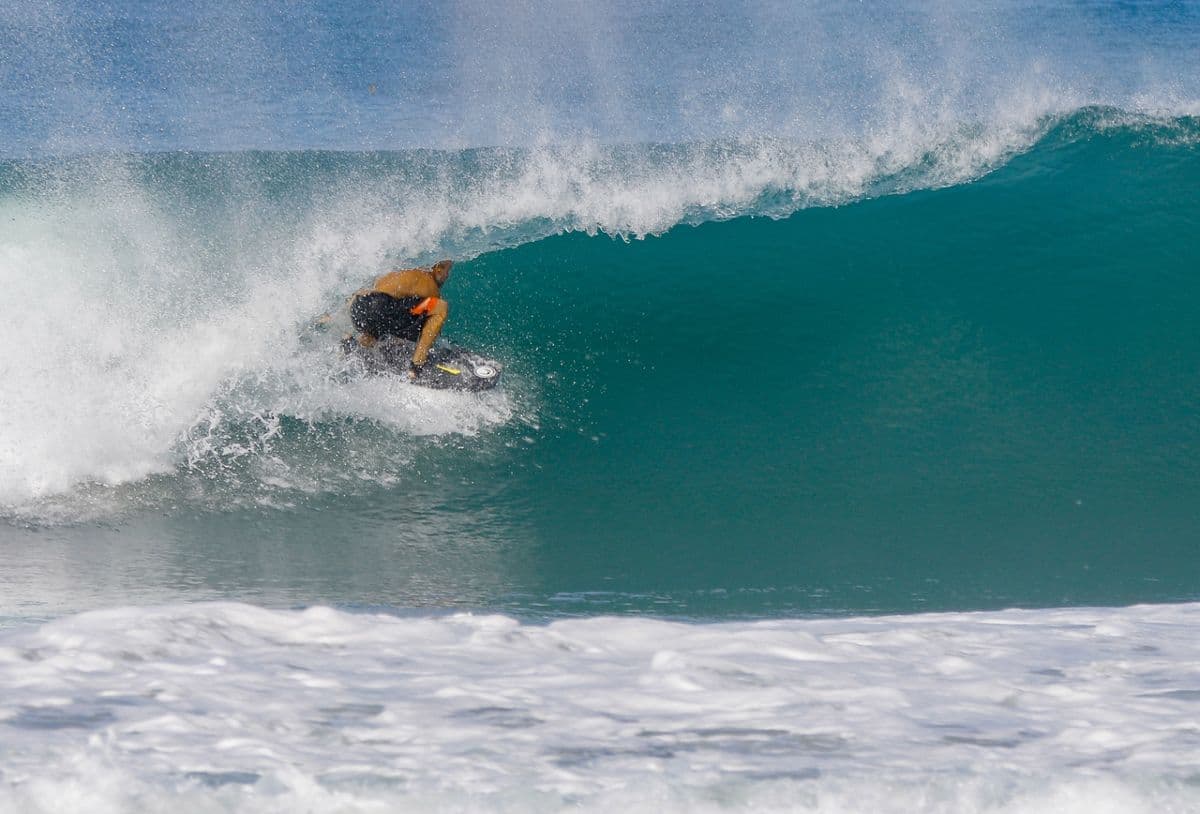Surfer rides inside a perfect blue barrel.