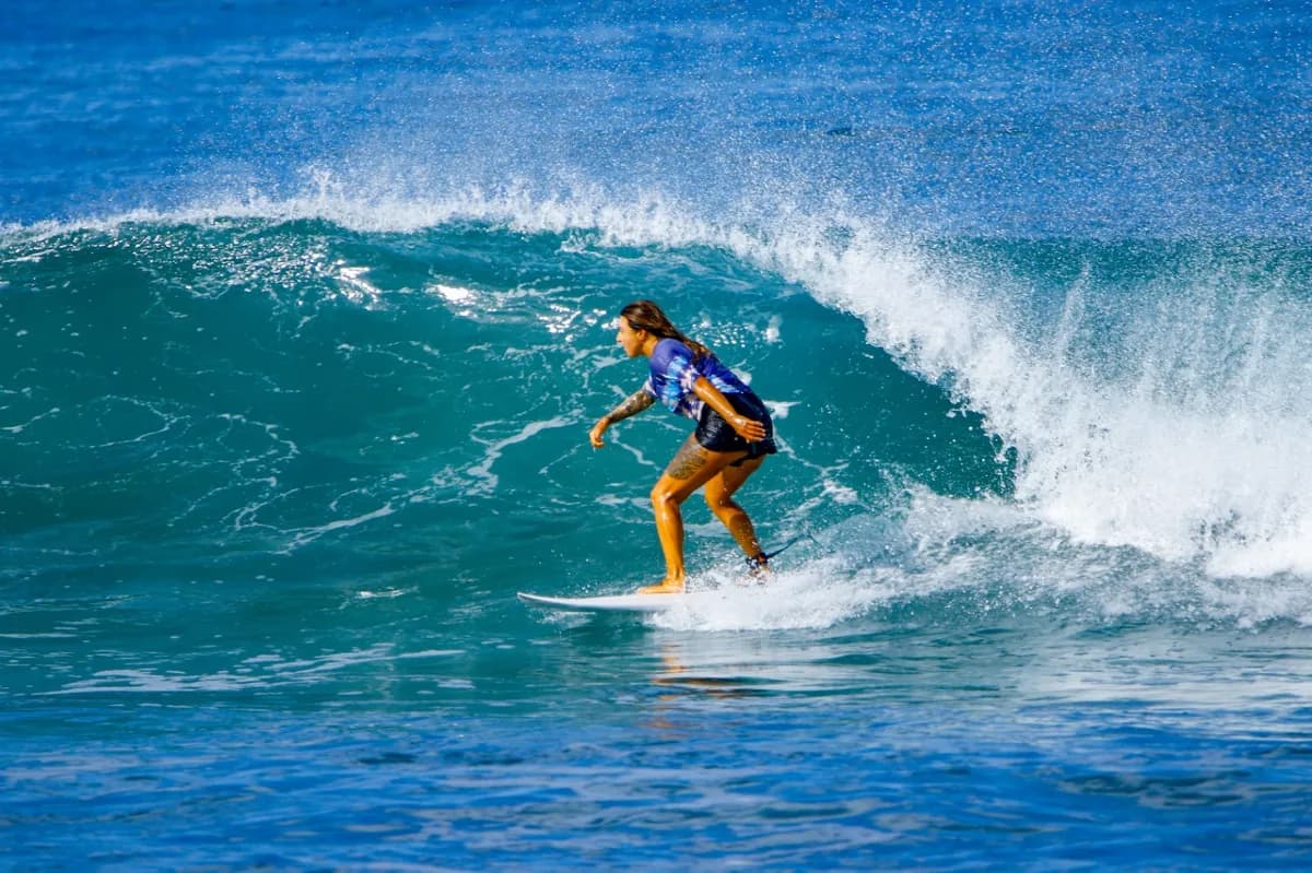 Surfer rides a glassy wave with focused determination.