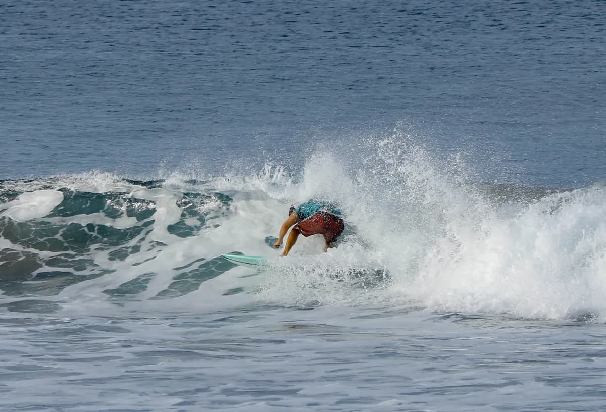 Surfer executes a powerful bottom turn on a small wave.
