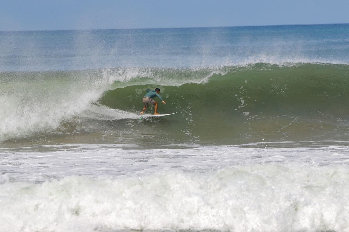 Surfer skillfully rides inside a perfect wave barrel.