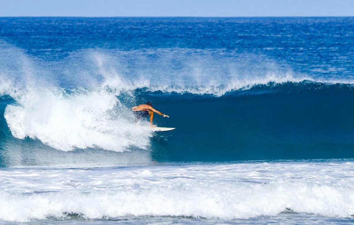 Surfer skillfully rides a smooth, blue wave with style.