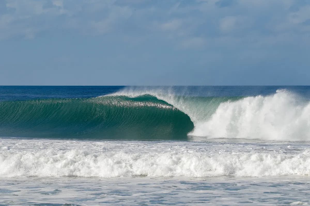 Perfect empty wave barrels under a blue sky.