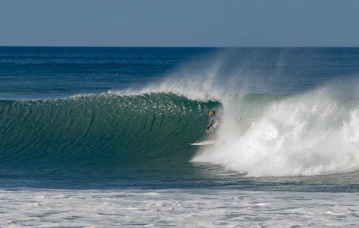 Surfer riding a perfect barrel with spray all around.