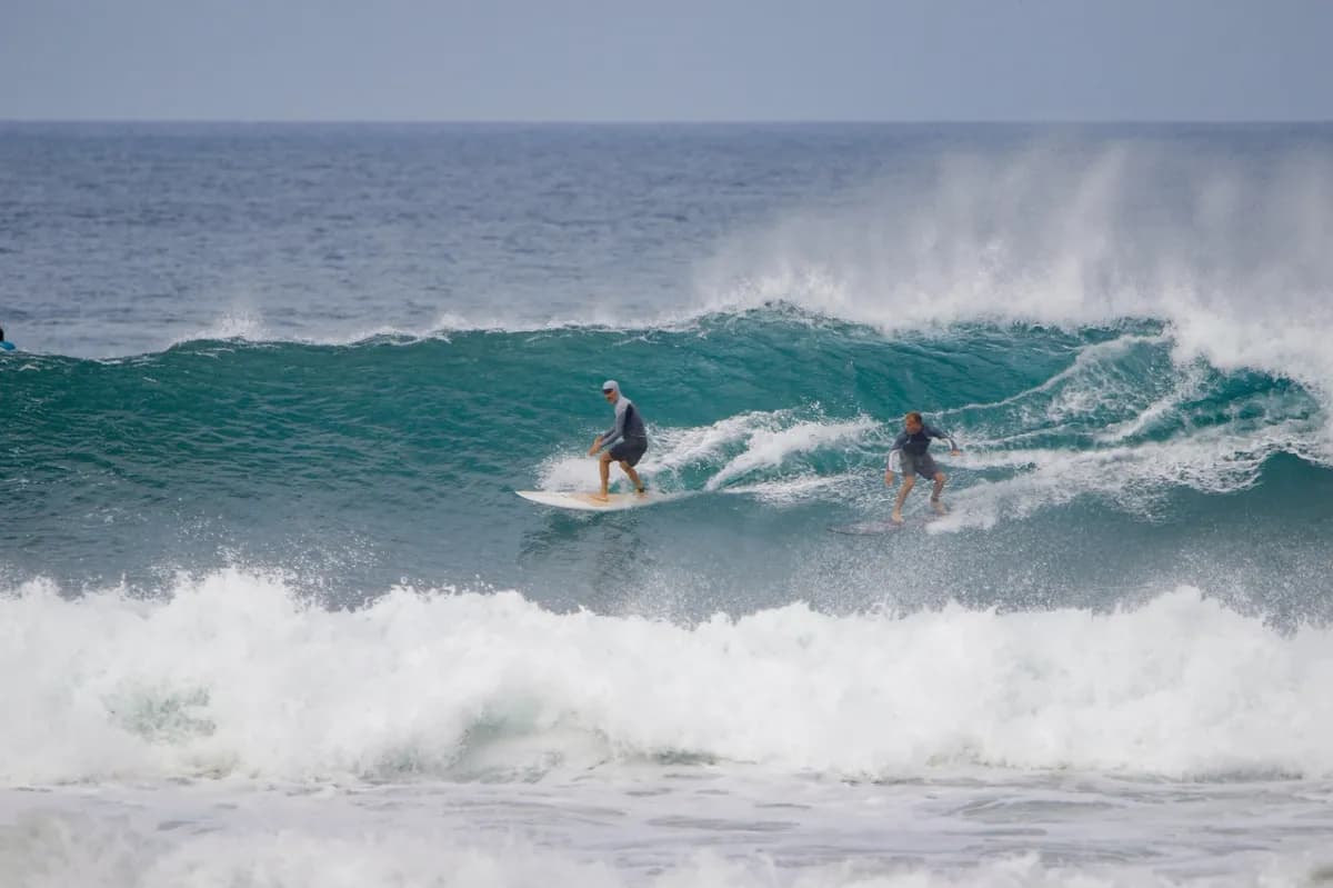 Two surfers ride a powerful wave together.