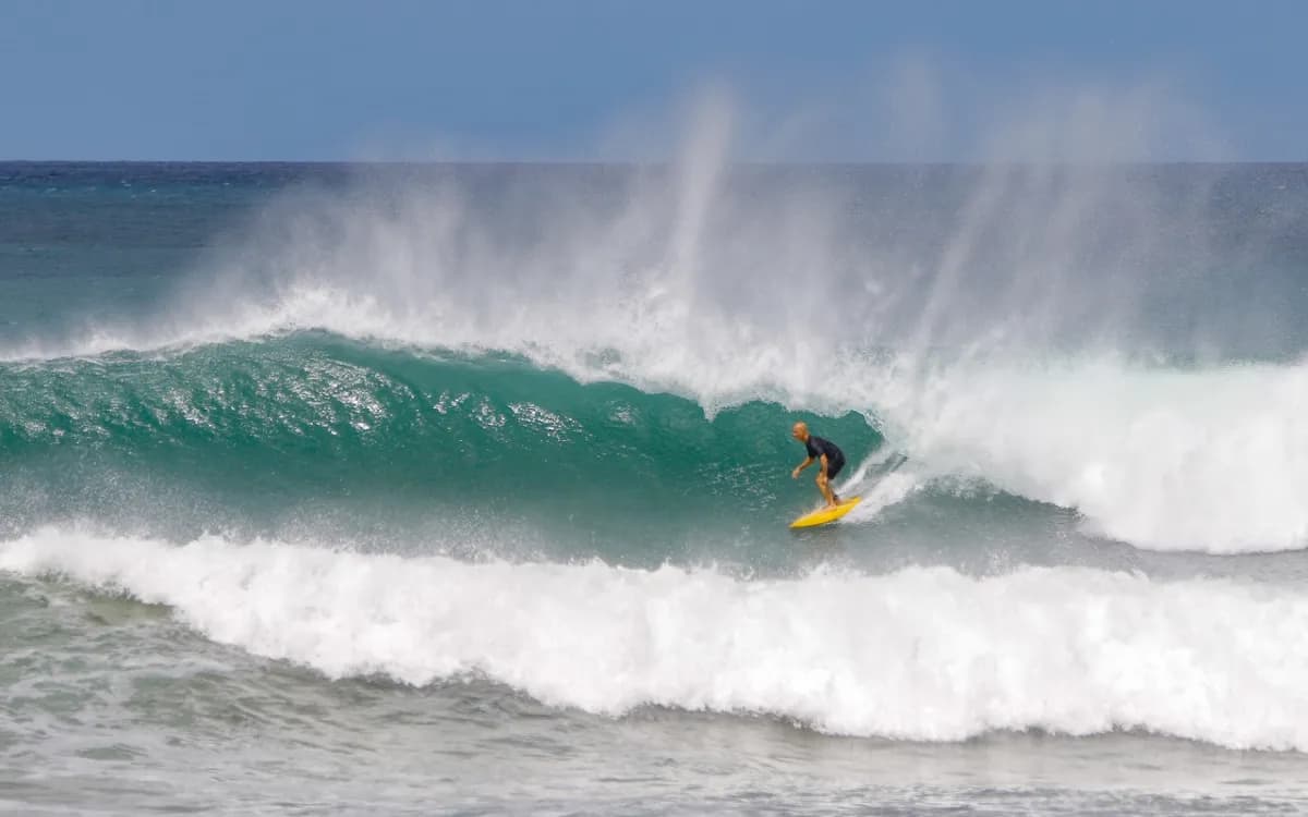 Surfer rides a powerful wave inside a barrel.
