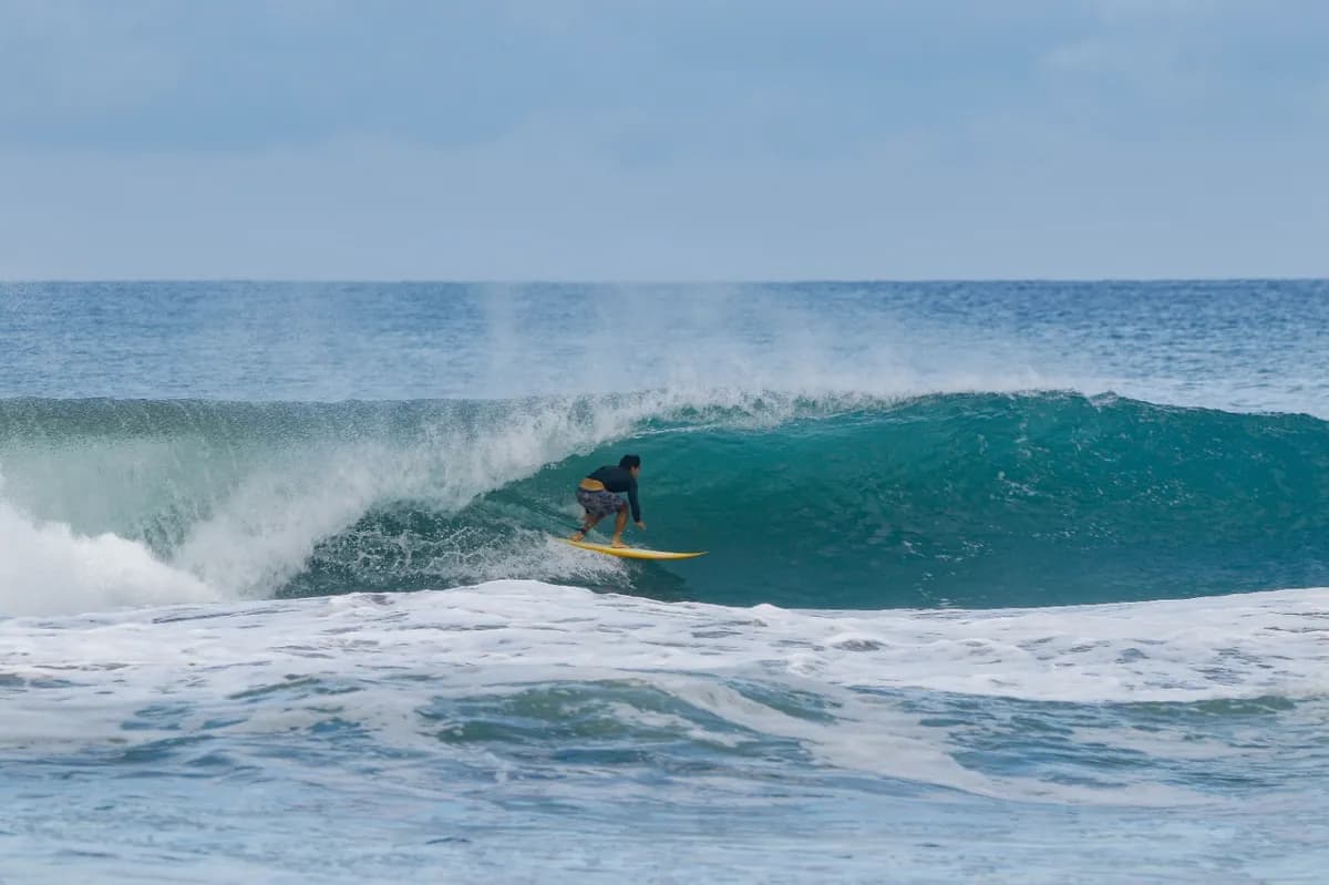 Surfer rides a vibrant blue wave inside a perfect barrel.