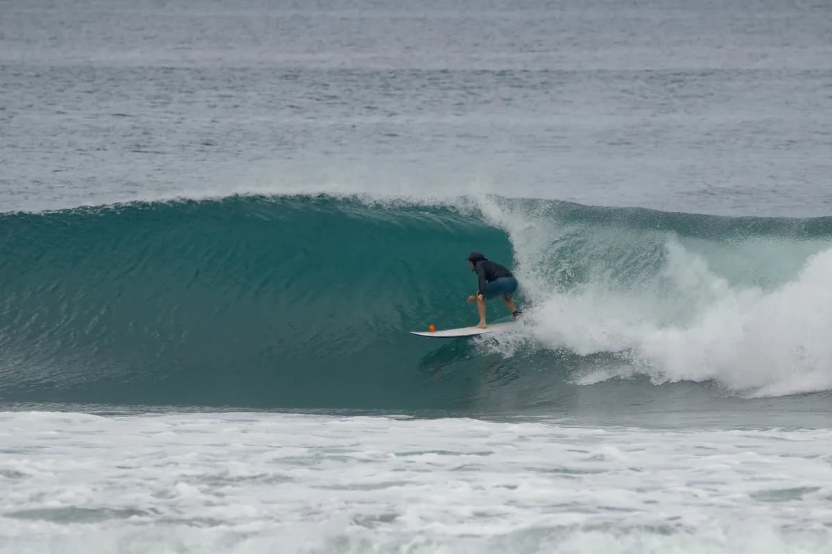 Surfer crouching in a perfect right barrel.