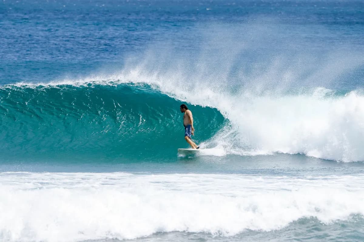 Surfer rides a perfect blue barrel with style.