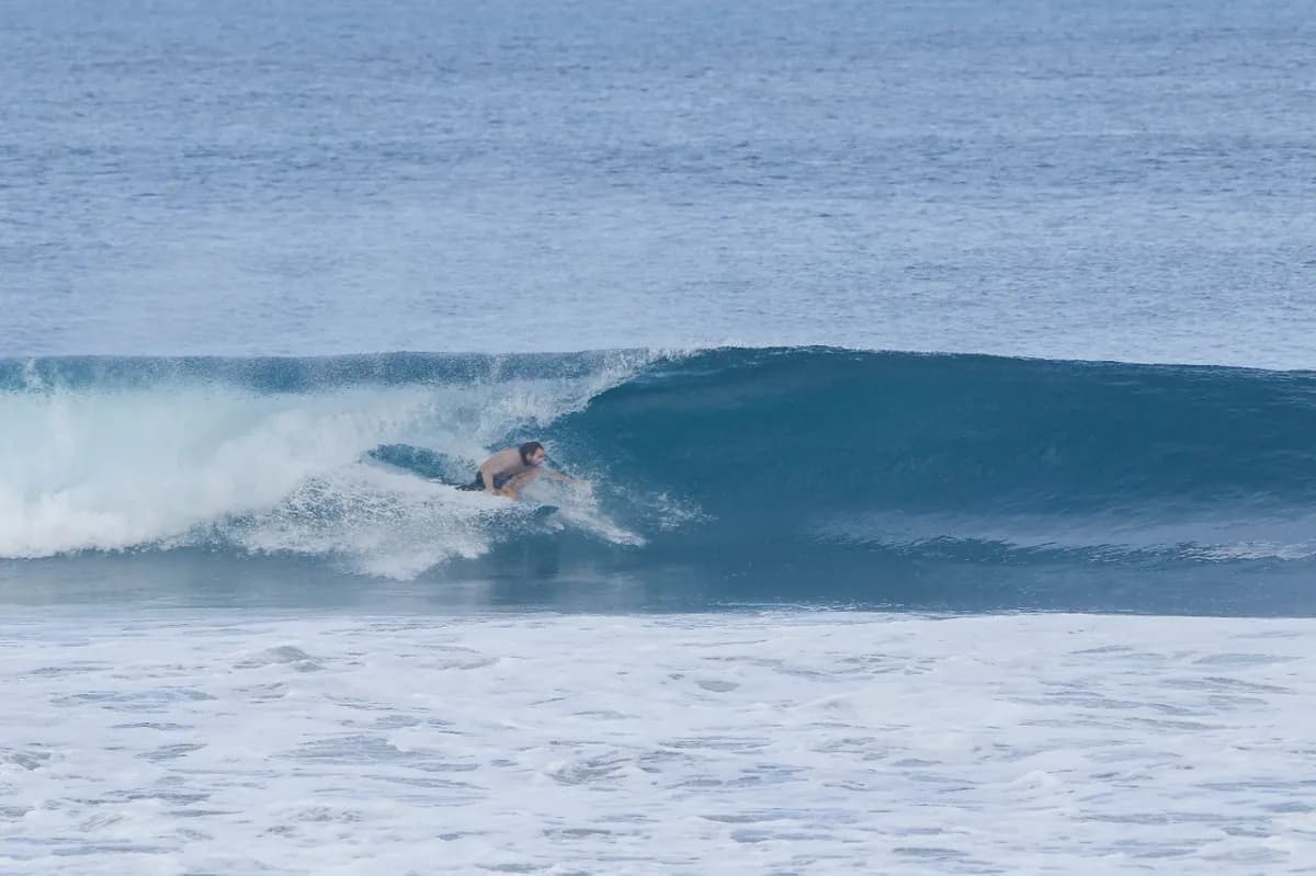 Surfer crouching inside a smooth glassy wave.
