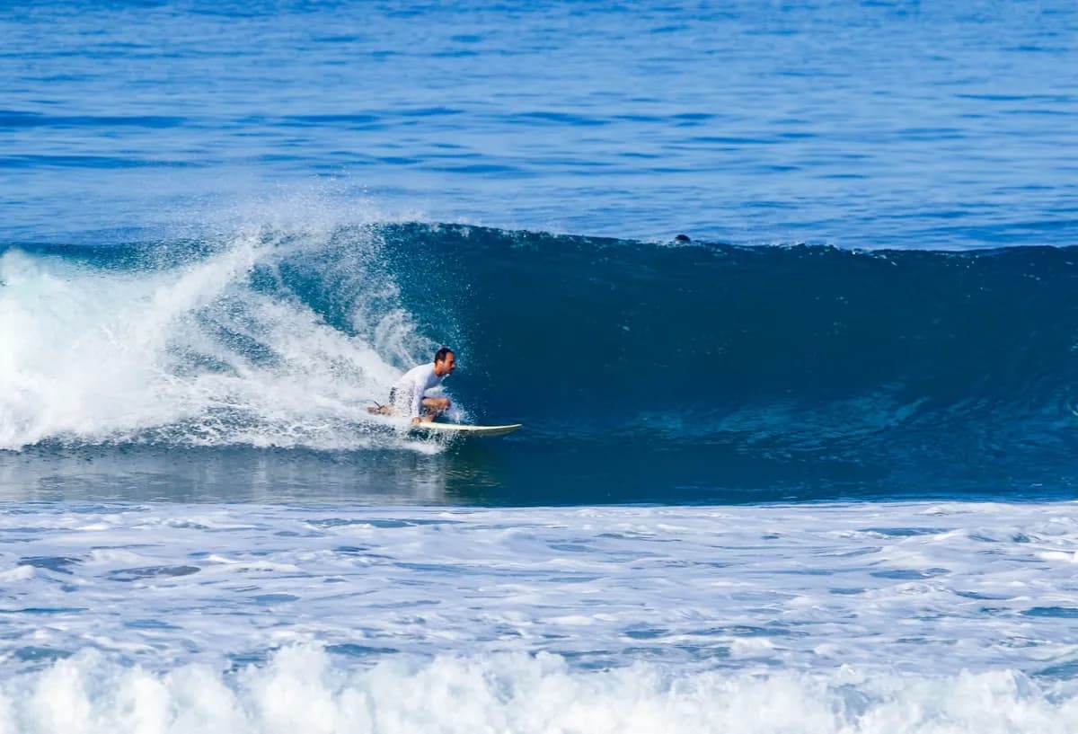 Surfer skillfully rides inside a blue barreling wave.