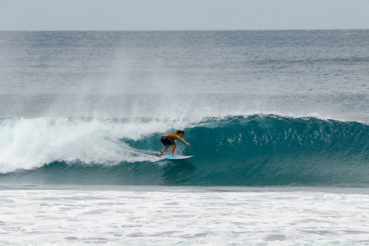 Surfer rides inside a perfect blue barrel wave.