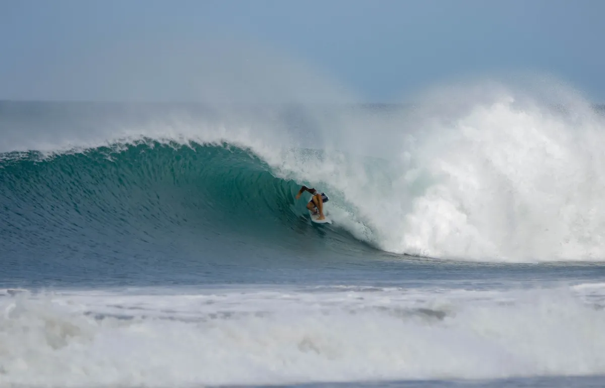 Surfer rides inside a perfect curling green wave.